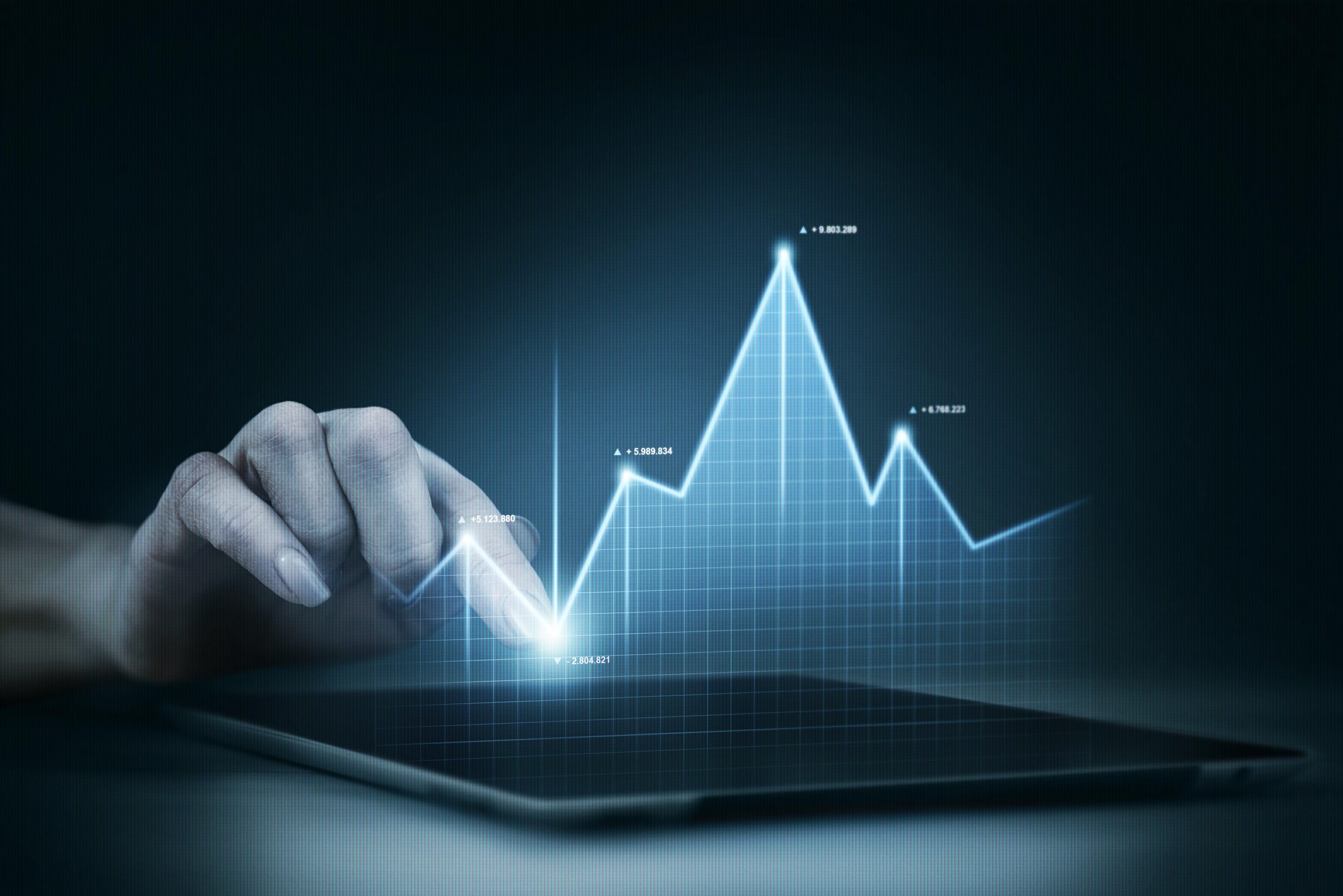 Hand interacting with digital holographic graph representing fintech trends for 2024